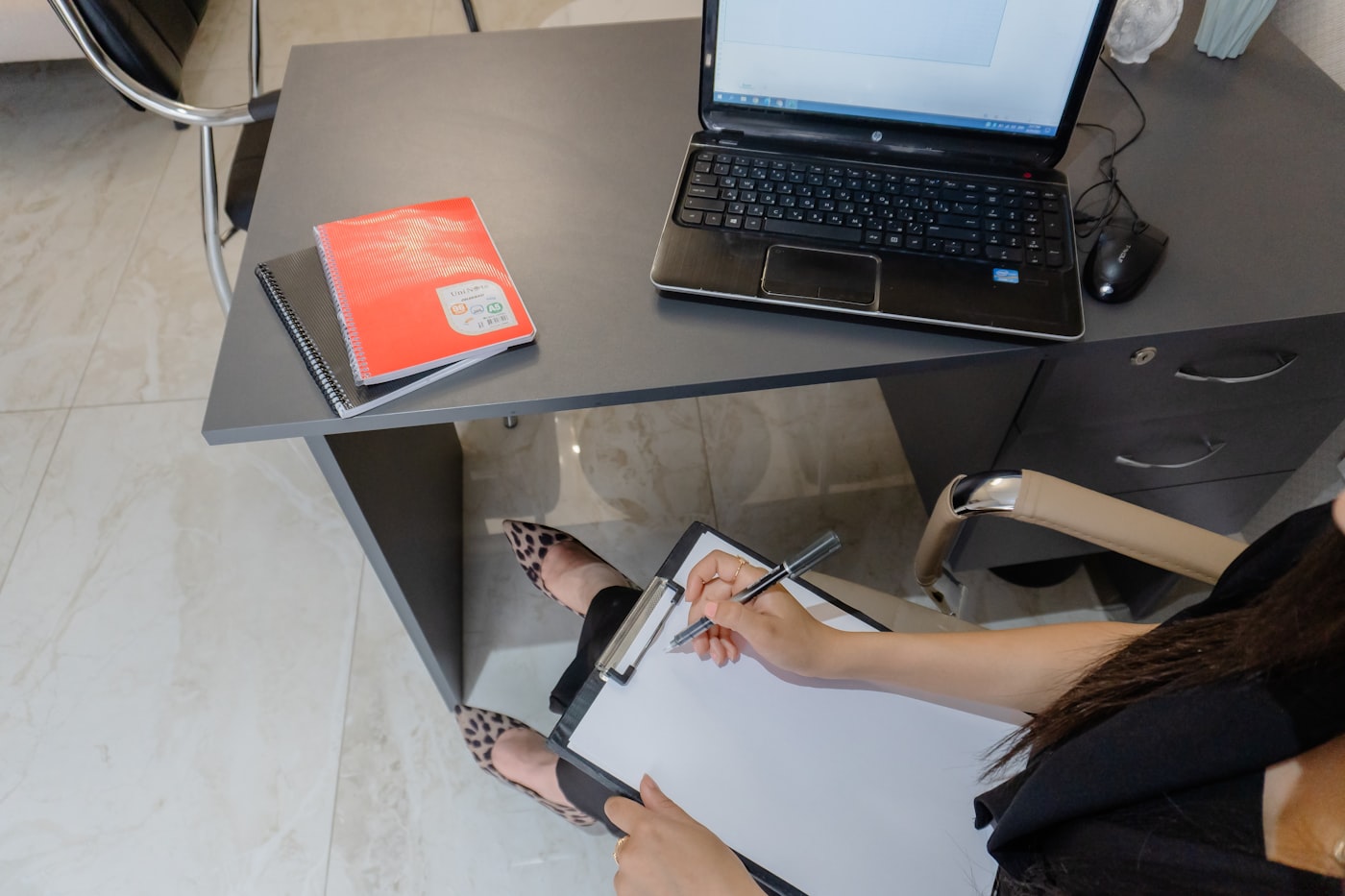 Trabajadora administrativa tomando notas en un escritorio pequeño